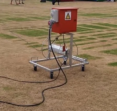 Portable orange power box on a wheeled cable reel trolley on a sports field