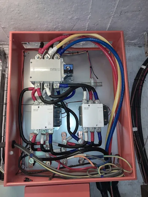 Enclosure with a changeover switch, two large contactors, busbars and heavy cabling