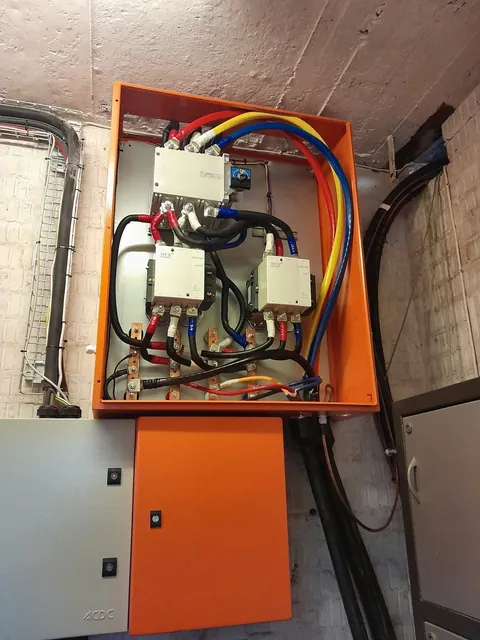 Orange enclosure with a changeover switch and two large contactors on a wall